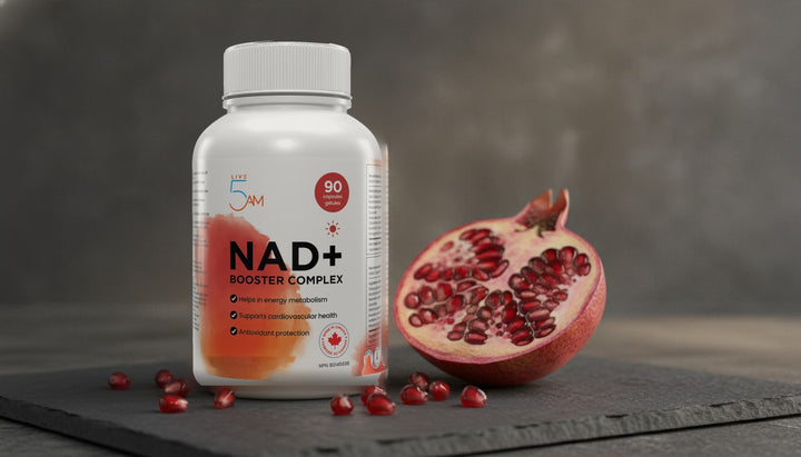 Live 5AM NAD+ Booster Complex bottle beside a halved pomegranate on a slate board