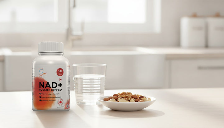 Live 5AM NAD+ Booster Complex bottle on a bright kitchen counter with a glass of water and a dish of nuts
