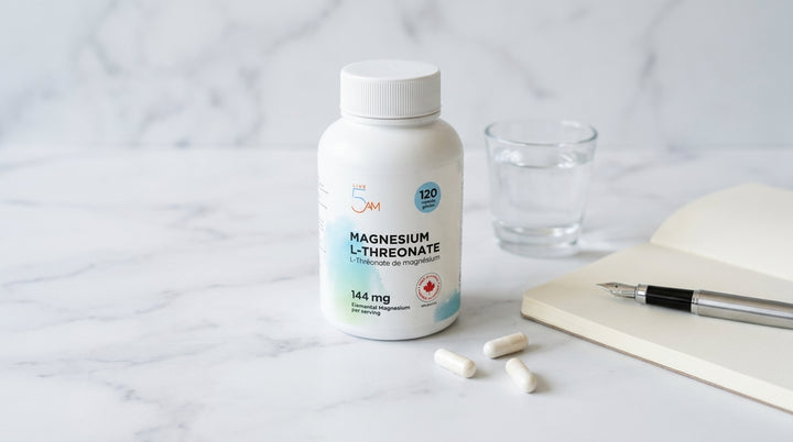 Magnesium L-Threonate bottle on white marble with glass of water, notepad, and white capsules in soft daylight
