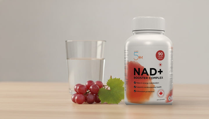 Live 5AM NAD+ Booster Complex bottle with red grapes and a grape leaf on a light wood table